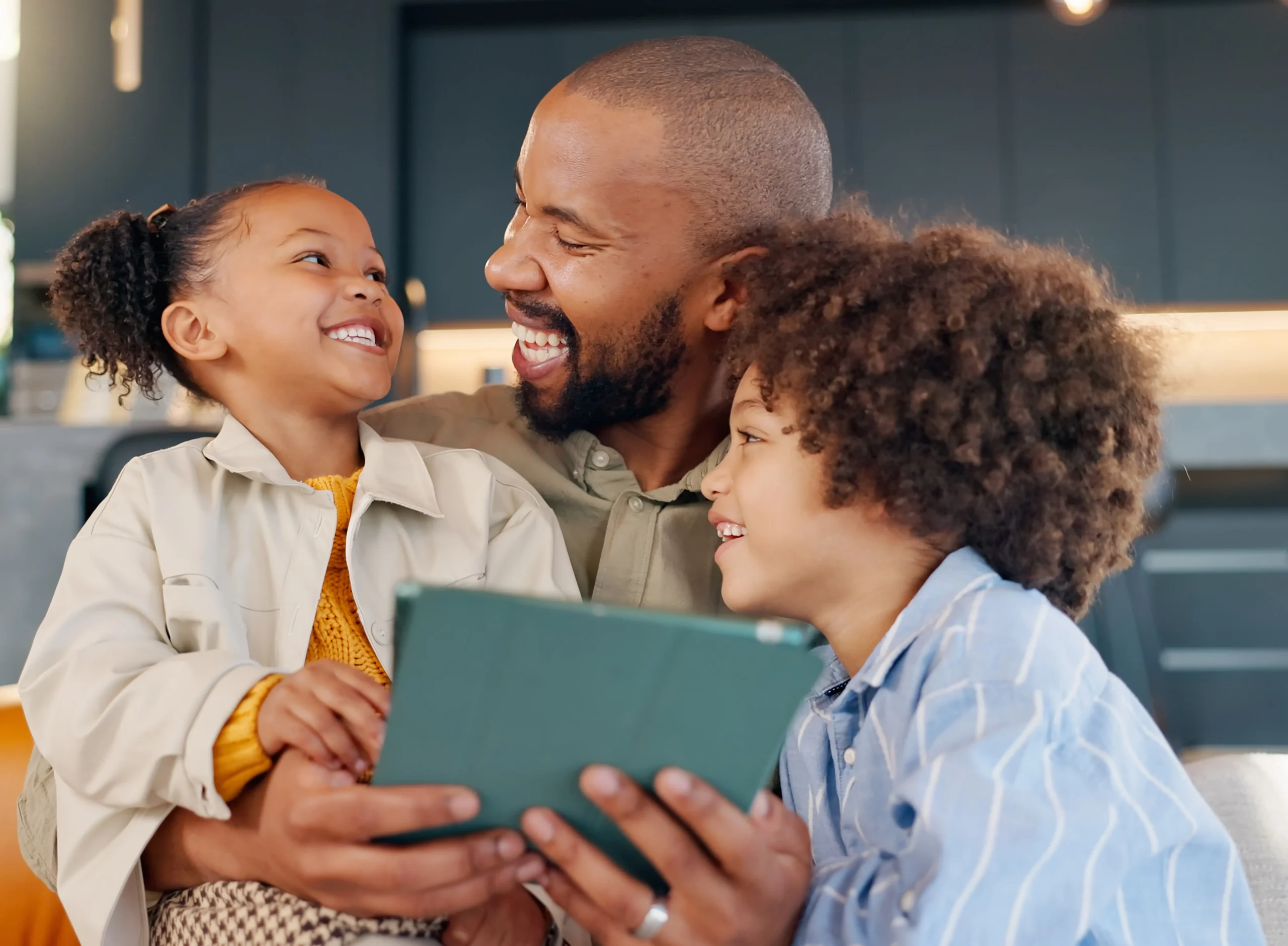 Smiling father spending quality time with his children while using a tablet together at home.